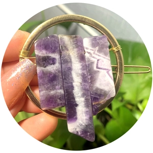 Golden circular hair clip with natural purple crystal stones on a bright background