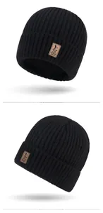 Detail showing black ribbed knit beanie with brown leather EDIKO patch and thick fold-up cuff