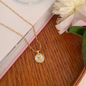 Detail of a gold tulip pendant with mother of pearl inlay on a natural wood surface