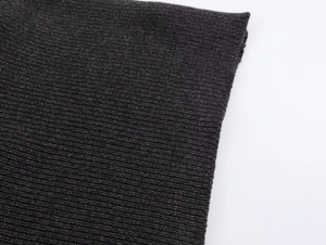 Detailopname van de geribbelde gebreide textuur en weefdetails van de asymmetrische poncho