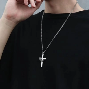 Detail shot of a punk style stainless steel cross and ring necklace on a black tee.