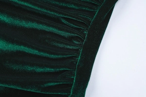 Detailed macro view of dark green velvet fabric with elegant pleated texture for dresses