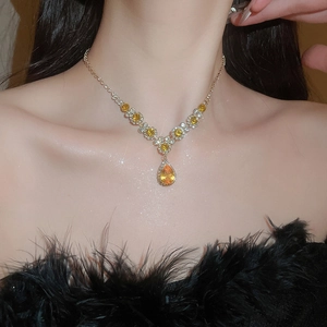 Detail of a vintage necklace with a yellow teardrop gemstone and gold chain on a model