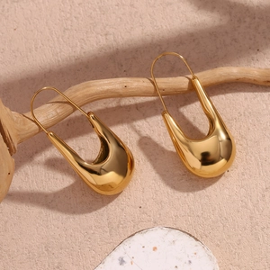 Détail de boucles d'oreilles en acier inoxydable doré en forme de U sur une branche