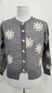Detail of grey knitted cardigan showing white daisy floral patterns and button closure