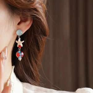 Close-up of ocean-style starfish earrings with blue beads and glass droplets on model