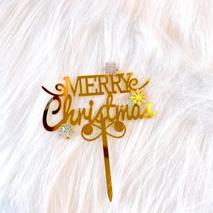 Golden acrylic Merry Christmas cake topper with iridescent snowflake details on white fur
