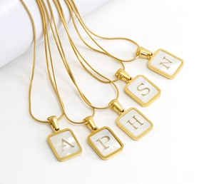 Detail of gold-plated titanium necklaces with white shell rectangular letter pendants