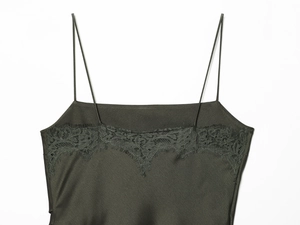 Détail du caraco en satin vert olive foncé avec bordure en dentelle sur fond blanc