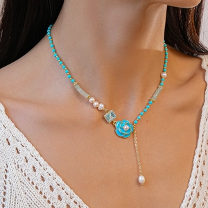 Elegant bohemian floral necklace with blue beads and pearls on a vintage knit sweater