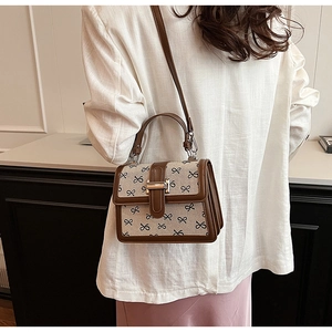 Dettaglio di una borsa a tracolla chic con stampa fiocco e finiture in pelle marrone