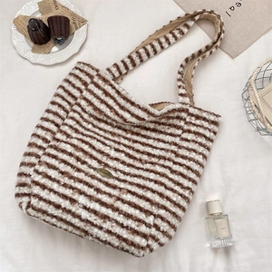 Detail of plush brown striped tote bag featuring soft faux fur texture and metal logo