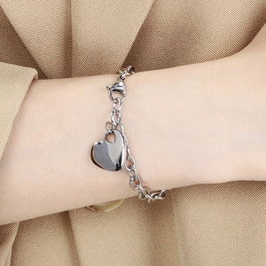 Detail of silver heart pendant bracelet with thick chain links on model's wrist