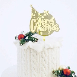 Close-up of golden acrylic Merry Christmas cake topper with tree and snowflake patterns