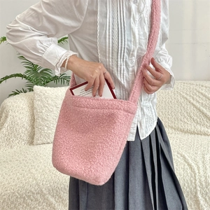 Gros plan du sac seau en peluche rose en fausse fourrure douce avec longue bandoulière