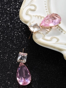 Pink teardrop gemstone drop earrings with gold finish on elegant white relief porcelain