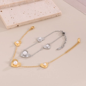 Detailed close-up of gold and silver heart bracelets featuring white shell pearls
