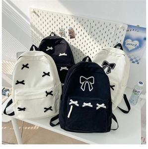 Detail of corduroy backpacks in black and beige with cute bow embroidery designs