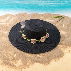 Detailed weave texture of black straw sun hat with decorative floral wreath and silk ribbon