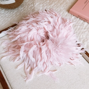 Gros plan d'un chouchou en plumes rose tendre posé sur un plateau à bijoux blanc
