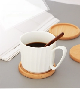 Detailed close-up of a round beech wood coaster with natural grain on a grey surface