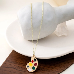 Artistic gold necklace with multi-color paint palette pendant on elegant wood texture
