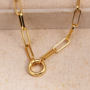 Close-up of gold plated paperclip chain with a circular ring connector on beige fabric