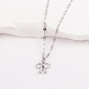Détail macro d'un pendentif papillon en argent avec zircons sur un socle en pierre blanche