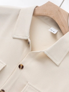 Macro detail of men's beige waffle knit shirt collar with button and texture