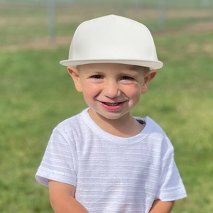 Outdoor shot of a boy wearing a white kids baseball cap and striped t-shirt