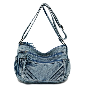 Detail of blue denim tote bag showing multiple zipper pockets and adjustable strap