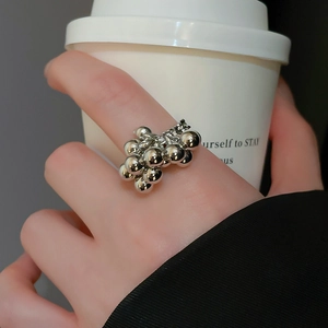 Close-up of a silver irregular multi-bead cluster ring worn on index finger in style