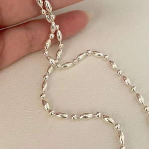 Macro detail of 925 sterling silver beaded necklace with polished oval and round beads