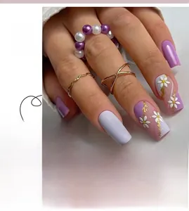 Detail of purple french tip press-on nails with white flower accents and gold glitter