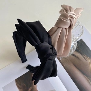 Detailed close-up of satin bow headbands in black and champagne with silk texture