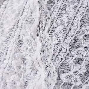 Close-up of intricate white crochet lace fabric with scalloped edges and floral patterns
