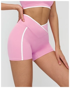 Détail du short de yoga rose à taille haute avec ceinture croisée en V et bandes blanches