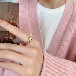 Close-up of a gold-plated pearl open ring set worn by a model in a pink knit sweater
