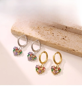 Détail de boucles d'oreilles cœur en or et argent avec zircons colorés sur support pierre