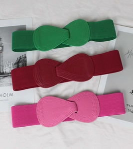 Close-up of three elastic belts in green, red, and pink with stylish bow buckles on top