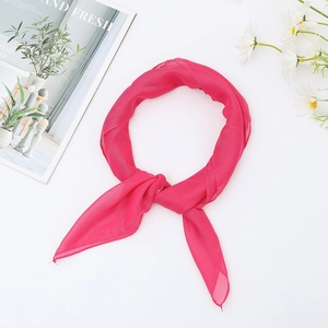 Detail of pink chiffon square scarf tied in a knot with floral and magazine accents