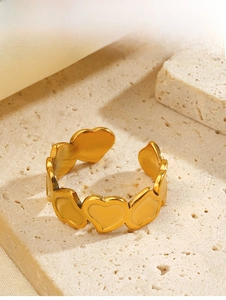 Close-up of golden hollow heart ring on stone surface with elegant textures