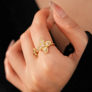 Détail d'une bague trèfle dorée avec fleurs en zircone sur la main du modèle