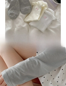 Detail of white and grey socks featuring ruffled edges and pink heart embroidery detail