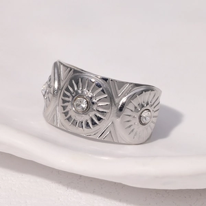 Vue macro de la bague large en acier argenté avec motif rayons de soleil et trois zircons
