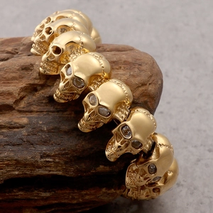 Gold skull head bracelet for men in stainless steel with crystal eyes on rustic wood