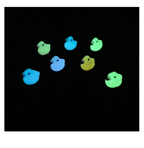 Luminous resin flamingo figurines glowing in blue, green, and yellow on a black background