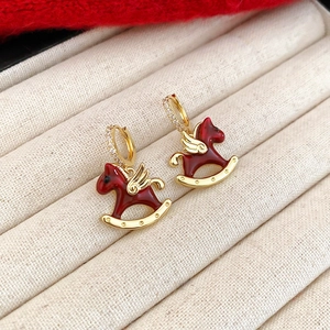 Vue macro de boucles d'oreilles cheval en émail rouge et plaqué or sur un plateau