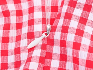 Makroaufnahme von rot-weißem Gingham-Stoff mit weißem unsichtbarem Reißverschluss