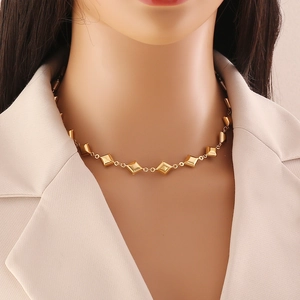 Golden geometric necklace with rhombus pendants on a model wearing a beige blazer